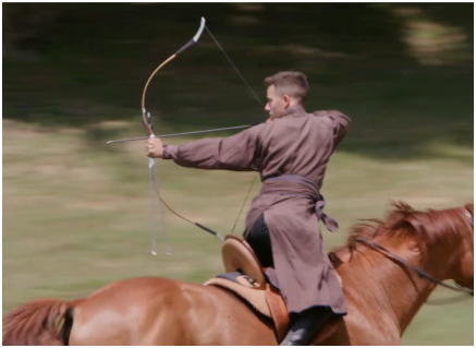 archer sitting on a horse shoots an arrow backwards